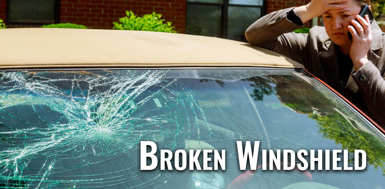 woman making a call by a broken windshield